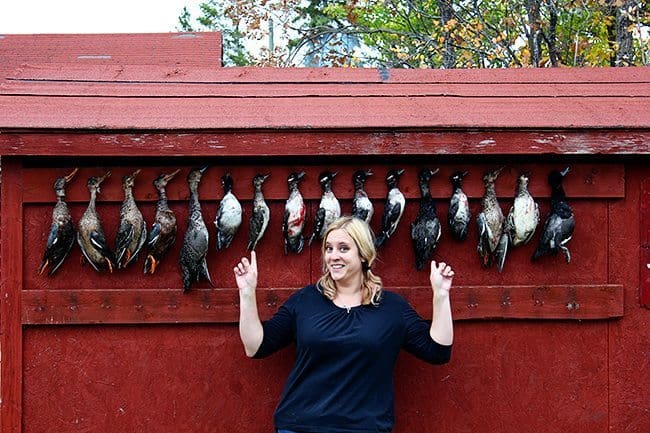 woman standing in front of requisite duck wall where different kinds of ducks are hanging