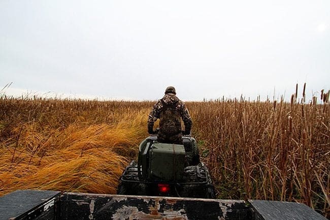 man wearing duck hunting gear driving a hooked up trailer