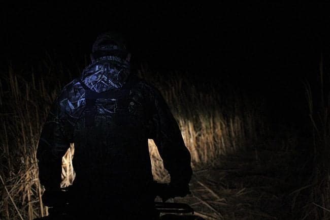 man walking on the marsh in the dark