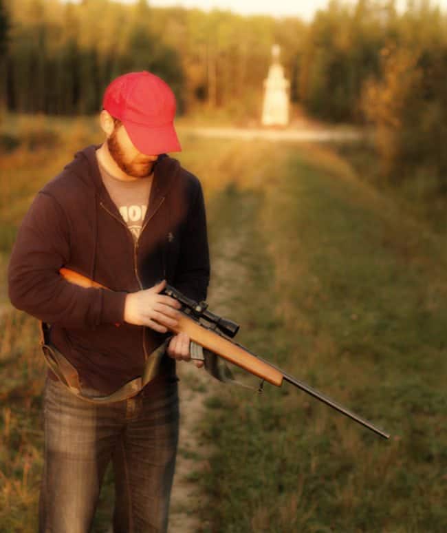 man wearing red cap preparing his riffle for ruffed grouse hunting