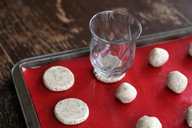 using a glass to flatten the Candy Cane Cookies dough