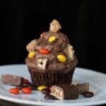 Buttercream Icing with chopped up candy bars on top of chocolate cupcake in a plate