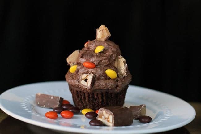 Buttercream Icing with chopped up candy bars on top of chocolate cupcake in a plate