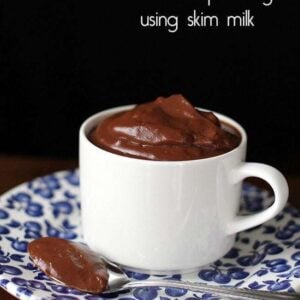 a white mug in a small blue designed plate with chocolate pudding made using skim milk
