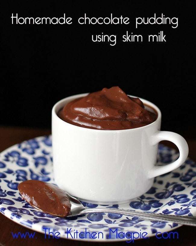 a white mug in a small blue designed plate with chocolate pudding made using skim milk