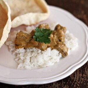 Close up of Pappadums and a Curry Sauce Served with Rice in a White Plate