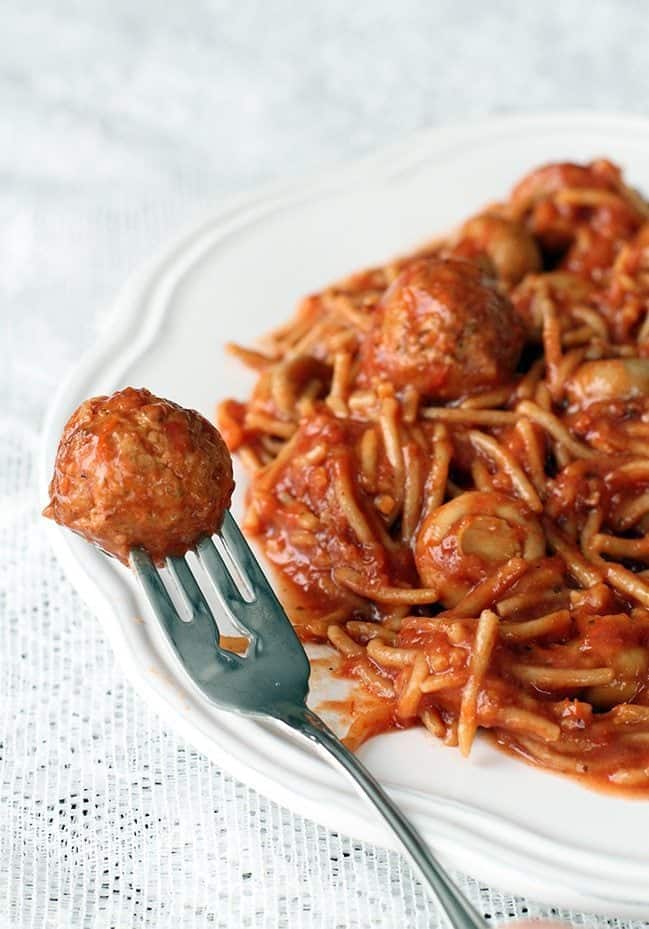 Close up of Meatballs in a fork from Crock Pot Spaghetti in white Plate on White tablecloth
