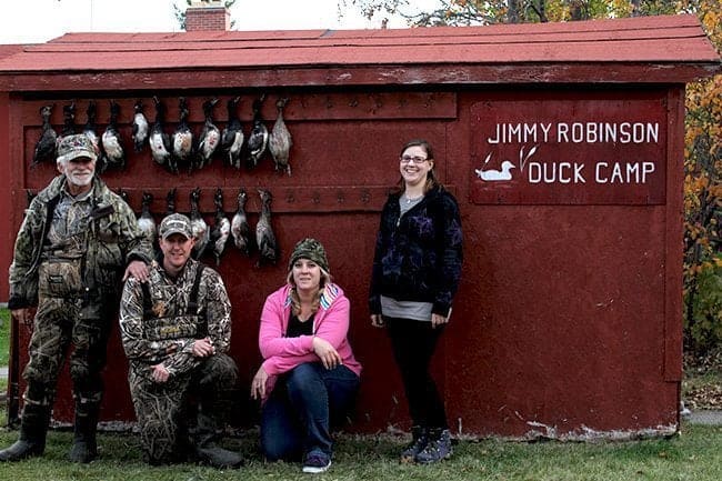 family photo of father and siblings with hanging ducks at the background