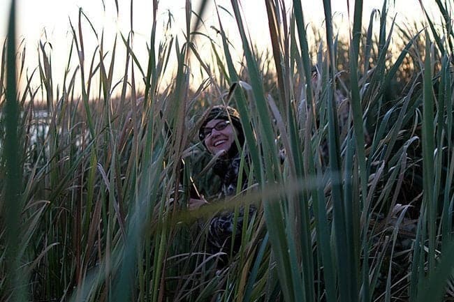 woman wearing her duck hunting gears hiding on the tall grasses
