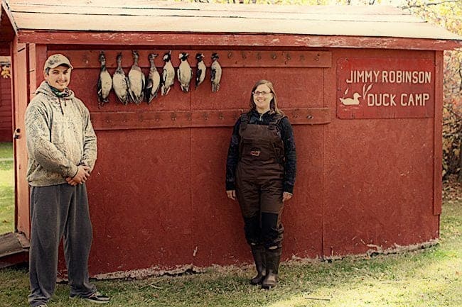 Man and woman standing in each side of hanging four widgeons, three bufflehead and one bluebill