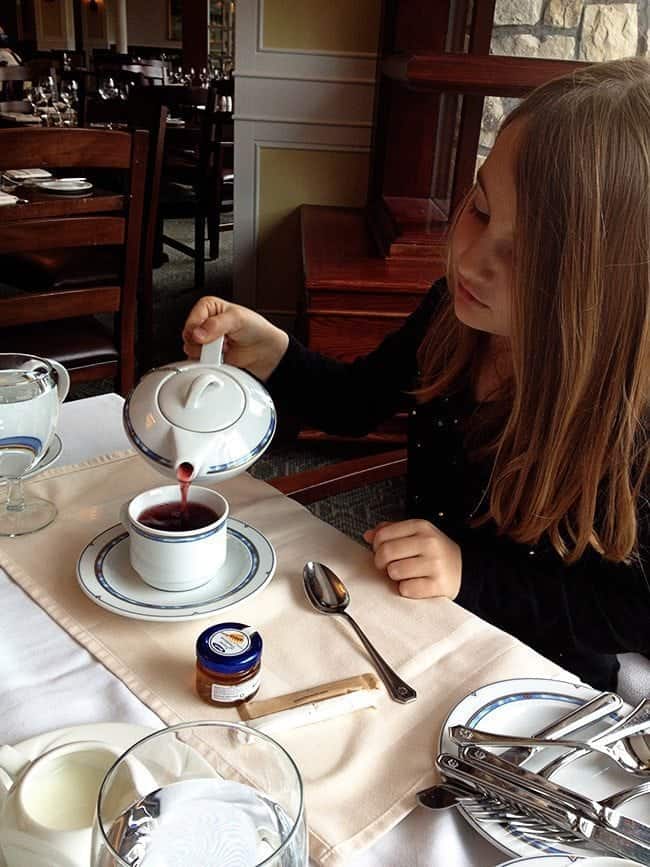 little girl pouring her own hot tea in her white cup