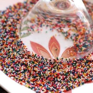 Eggnog Martini glass upside down into a plate of colorful sprinkles