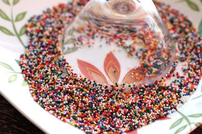 Eggnog Martini glass upside down into a plate of colorful sprinkles