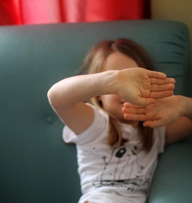 little girl covering her face with her two hands