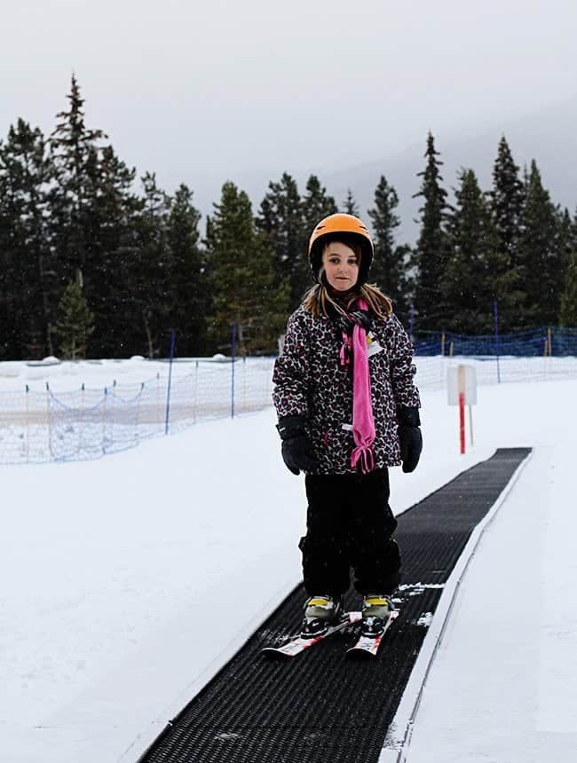 little girl wearing her skiing gear on her skiing board