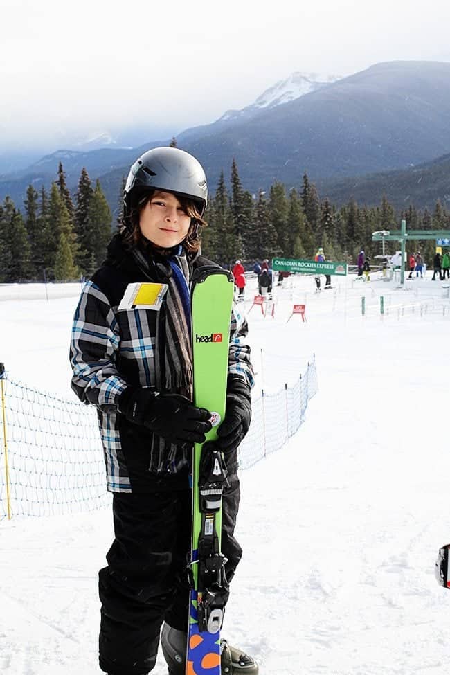 little boy in skiing gear holding his skiing board