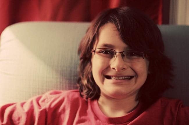 young boy sitting the couch wearing his new glasses