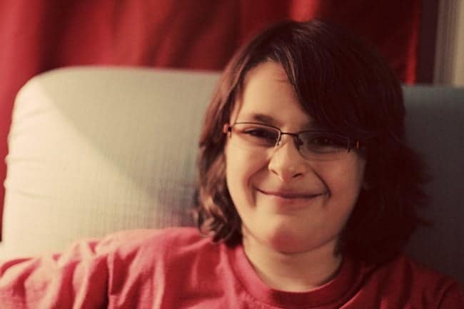 young boy sitting the couch wearing his new glasses snarls at the camera