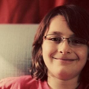 young boy wearing eye glasses, smiling while sitting in the couch