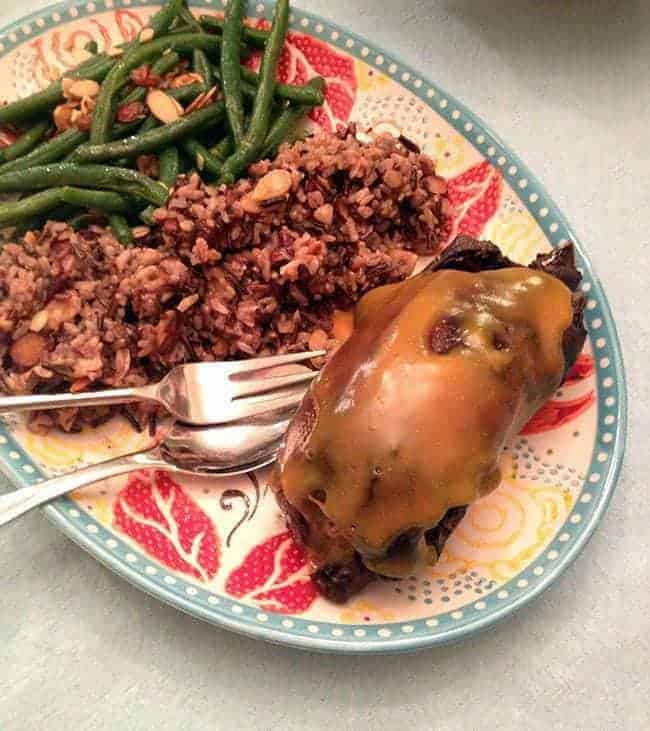 plate with braised wild duck, rice and almond green beans with a delicious orange sauce over it