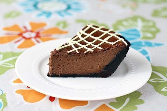 white plate with a slice of triple chocolate pumpkin pie on a floral tablecloth