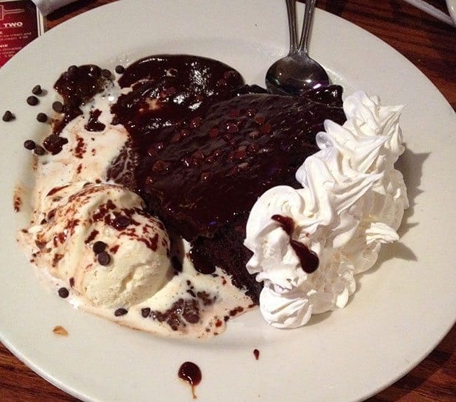 white plate with chocolate cake, scoops of ice cream and whipped cream