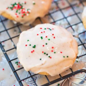close up glazed Eggnog Cookies topped with Christmas sprinkles on cooling rack