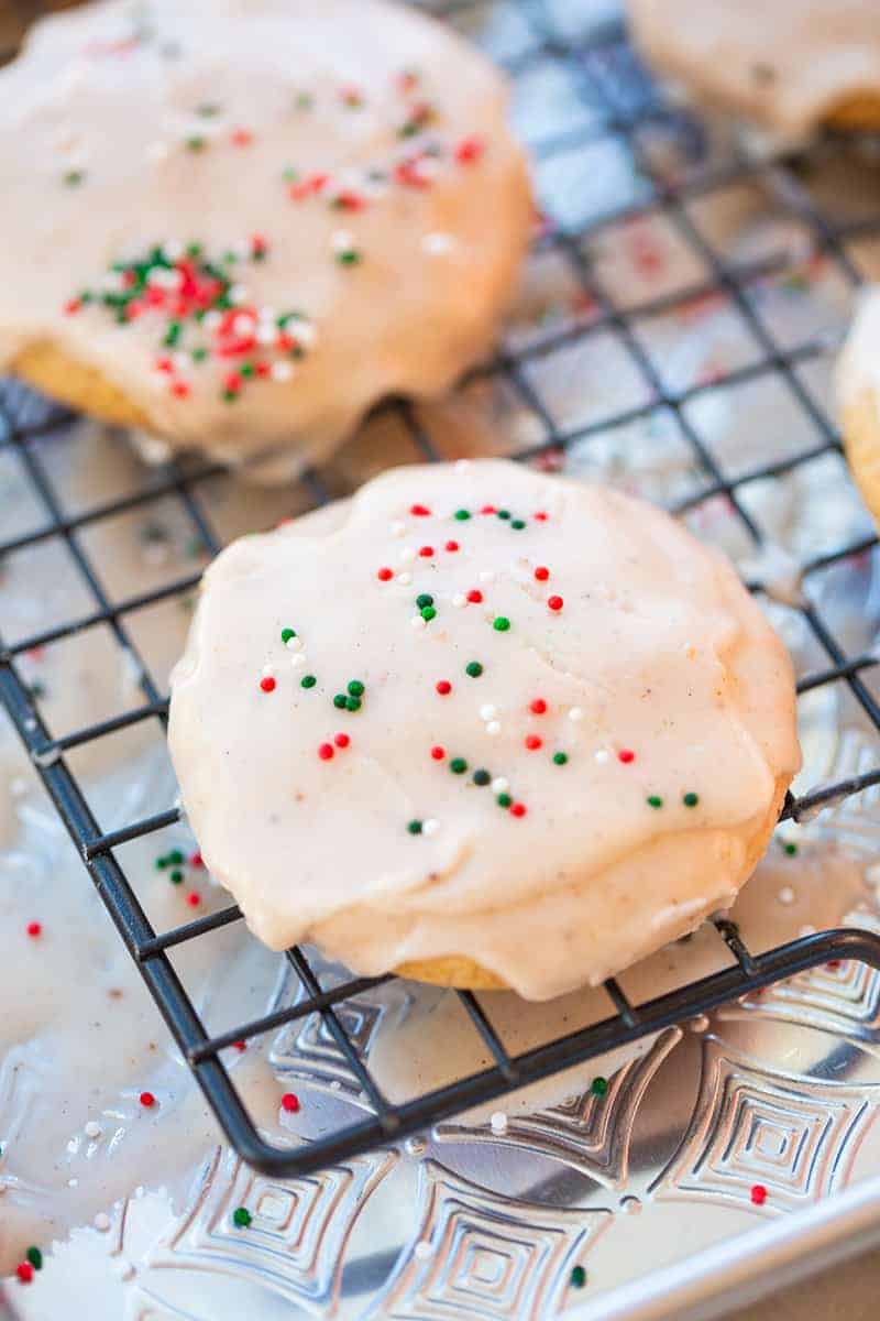 close up glazed Eggnog Cookies topped with Christmas sprinkles on cooling rack