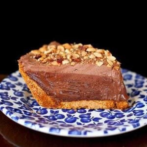 slice of hazelnut chocolate cream pie topped with crushed nuts in a small plate printed with blueberries