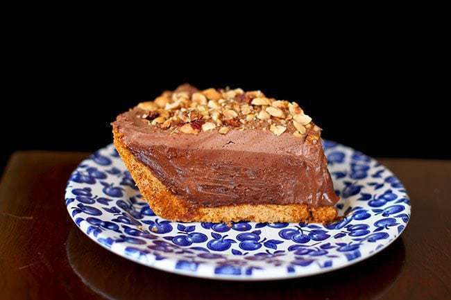 slice of hazelnut chocolate cream pie topped with crushed nuts in a small plate printed with blueberries