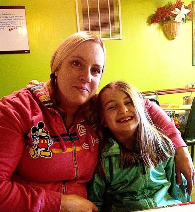 mom wearing red and daughter rearing green sitting inside the Red Iguana restaurant