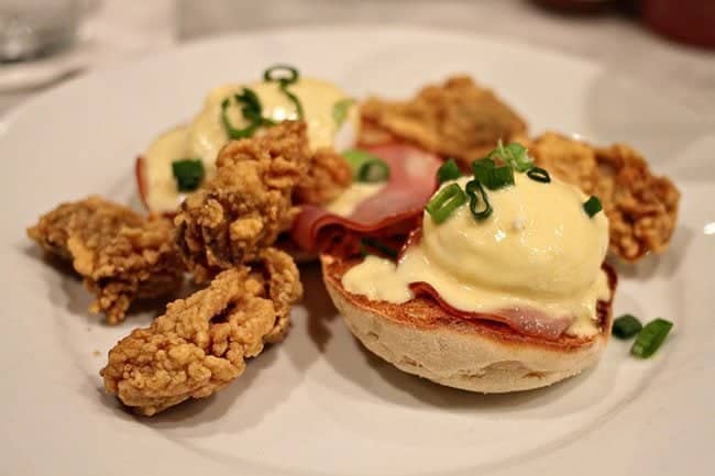 Eggs Benedict accompanied by fried cornmeal-crusted oysters with Hollandaise sauce