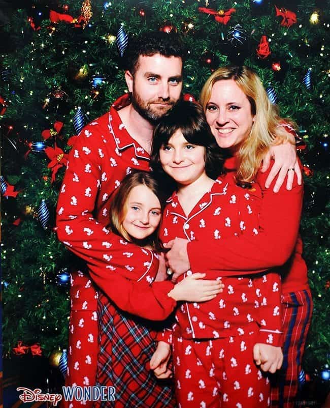 Family picture in red pajamas taken in front of the Christmas tree