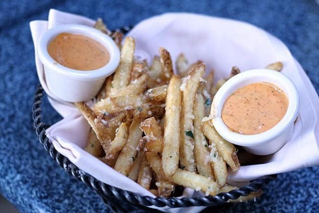 Pommes Frites - french fried potatoes tossed with Parmesan, garlic and parsley, served with a cajun spice rémoulade