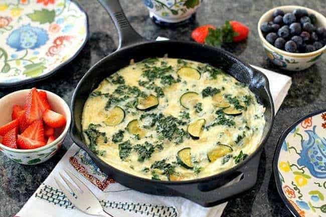Kale & Zucchini Frittata in skillet and some fresh berries in small bowls