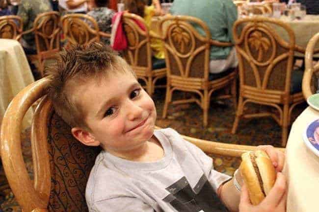 little boy sitting, holding his burger