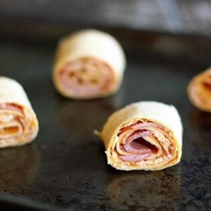 rolled up tortilla with pizza sauce, pepperoni slices sprinkled with cheese