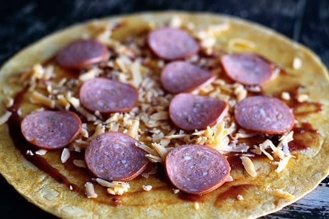 tortilla with pizza sauce, pepperoni slices sprinkled with cheese