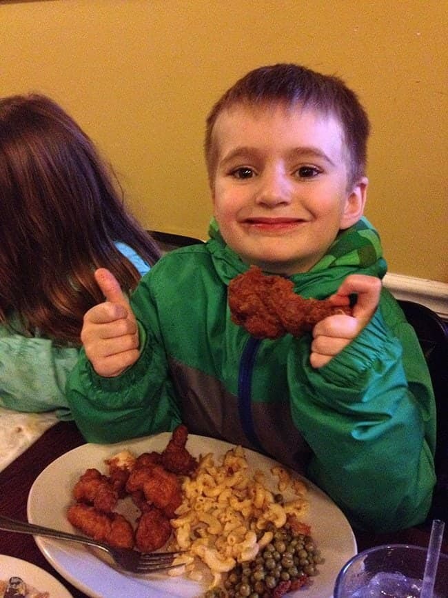 little boy holding a piece of crispy hot chicken at Willy Mae's Restaurant