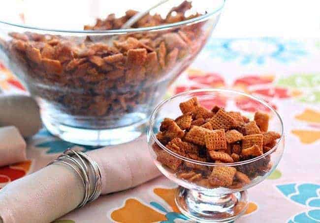 Bacon & Brown Sugar Chex Mix in a large transparent bowl with spoon and in transparent cup