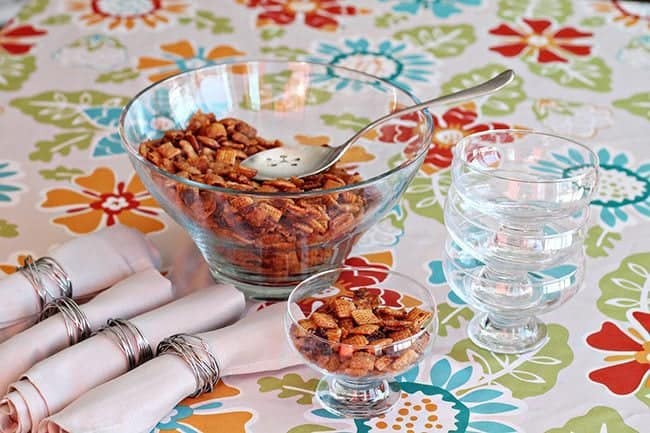 Bacon & Brown Sugar Chex Mix in a large transparent bowl with spoon and in transparent cup