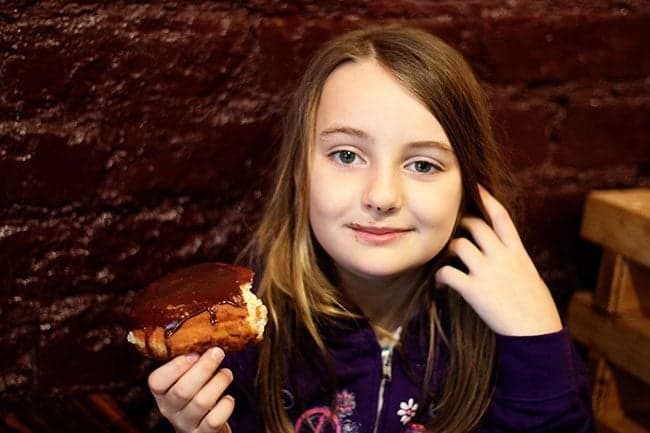 young girl holding her Boston cream donut 