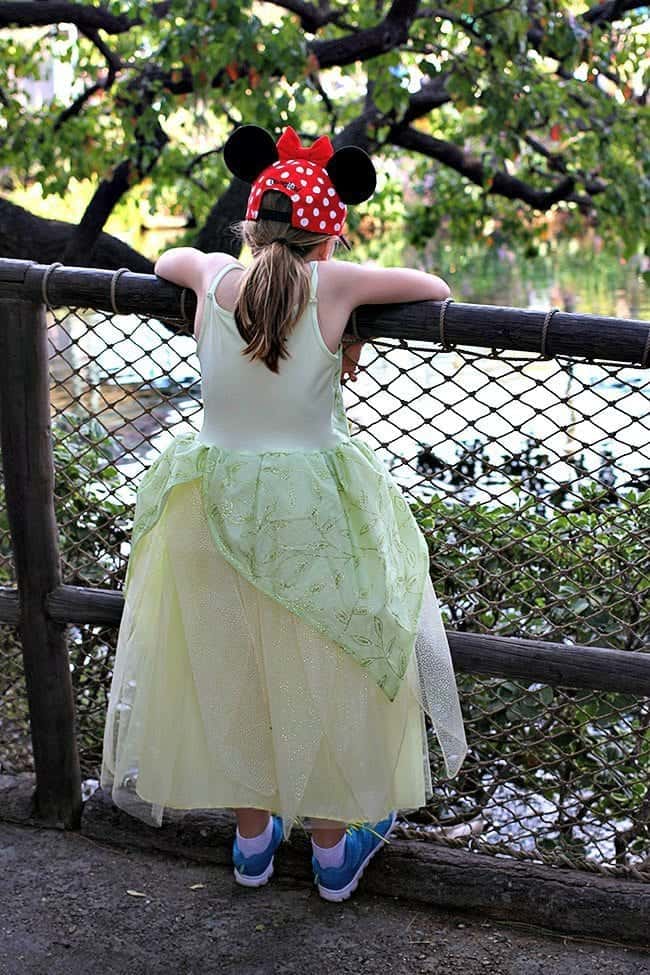 young girl wearing princess dress while trying to climb over a fence