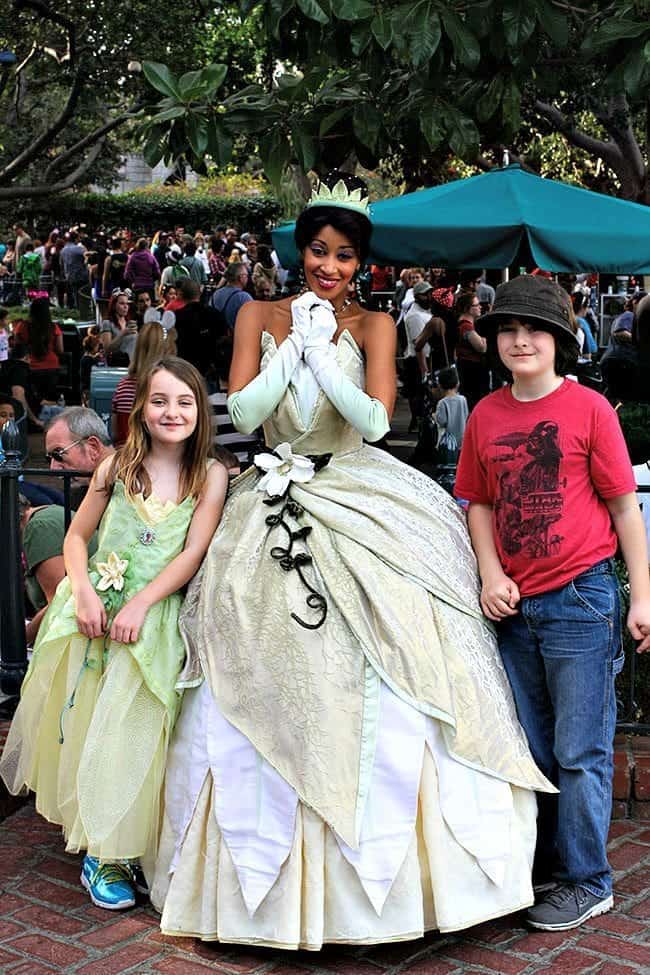young girl, princess Tiana and young boy with the crowd in their background