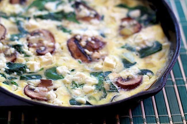 Close up of Spinach Mushroom Frittata in Skillet on a blue green mat