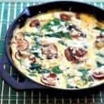 Close up of Spinach Mushroom Frittata in Skillet on a blue green mat