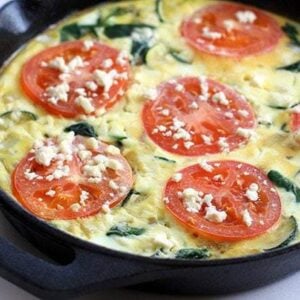 Close up Feta Frittata in a black skillet with Tomato and Spinach