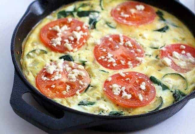 Close up Feta Frittata in a black skillet with Tomato and Spinach