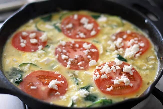 Close up Feta Frittata in a black skillet with Tomato and Spinach