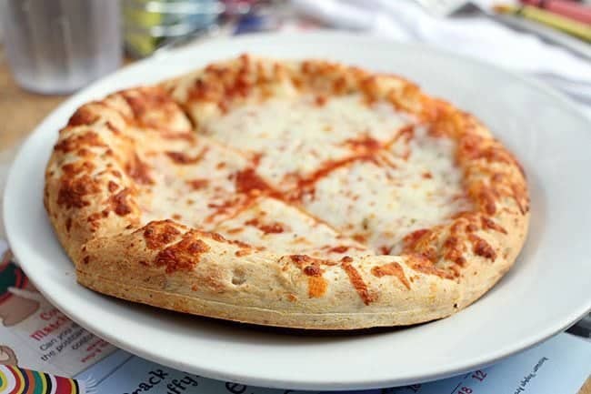 whole cheese pizza in a white plate